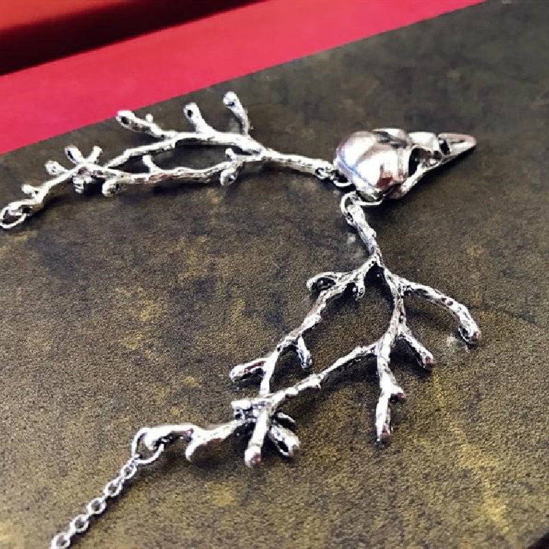 Ornement avec collier pendentif tête d'oiseau branche de crâne