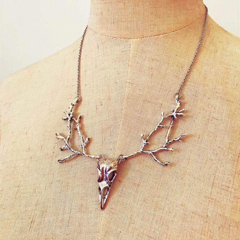 Ornement avec collier pendentif tête d'oiseau branche de crâne