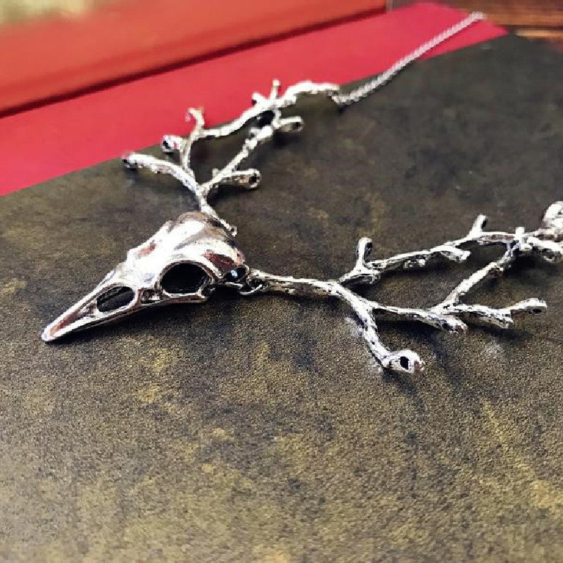 Ornement avec collier pendentif tête d'oiseau branche de crâne